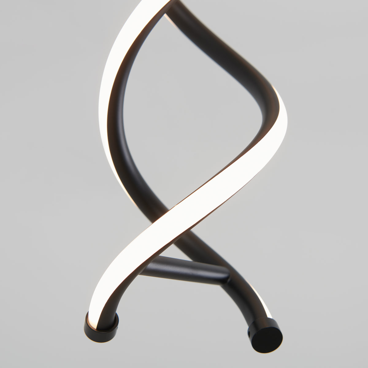 A close-up of a modern, spiral-shaped LED light fixture with two intertwined black and white bands against a plain gray background.