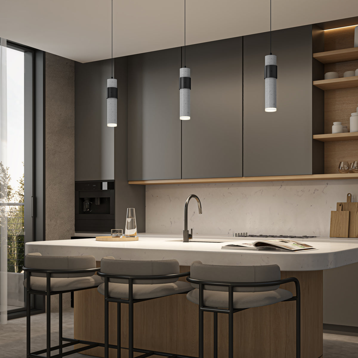 Modern kitchen with gray cabinets, a marble island, three cushioned bar stools, pendant lights, an open shelving unit, and a built-in oven. A glass water carafe and an open book sit on the island. Large window on the left.