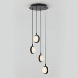 A modern ceiling light fixture with four round, illuminated pendants hanging at different lengths from a circular black base against a plain light gray background.