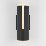 A modern cylindrical black wall sconce with narrow vertical light strips on the front and soft glow at the top and bottom, mounted on a light grey wall.