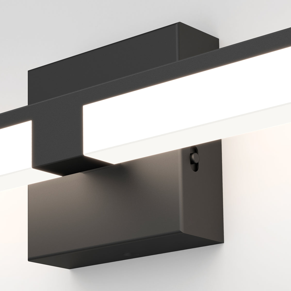 Close-up view of a modern, rectangular wall-mounted light fixture with a matte black base and a horizontal white LED light bar, attached to a white wall.