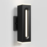 A modern black wall sconce with a rectangular shape, featuring a vertical cutout with an LED light inside and glowing edges on the top and bottom, mounted on a light gray wall.