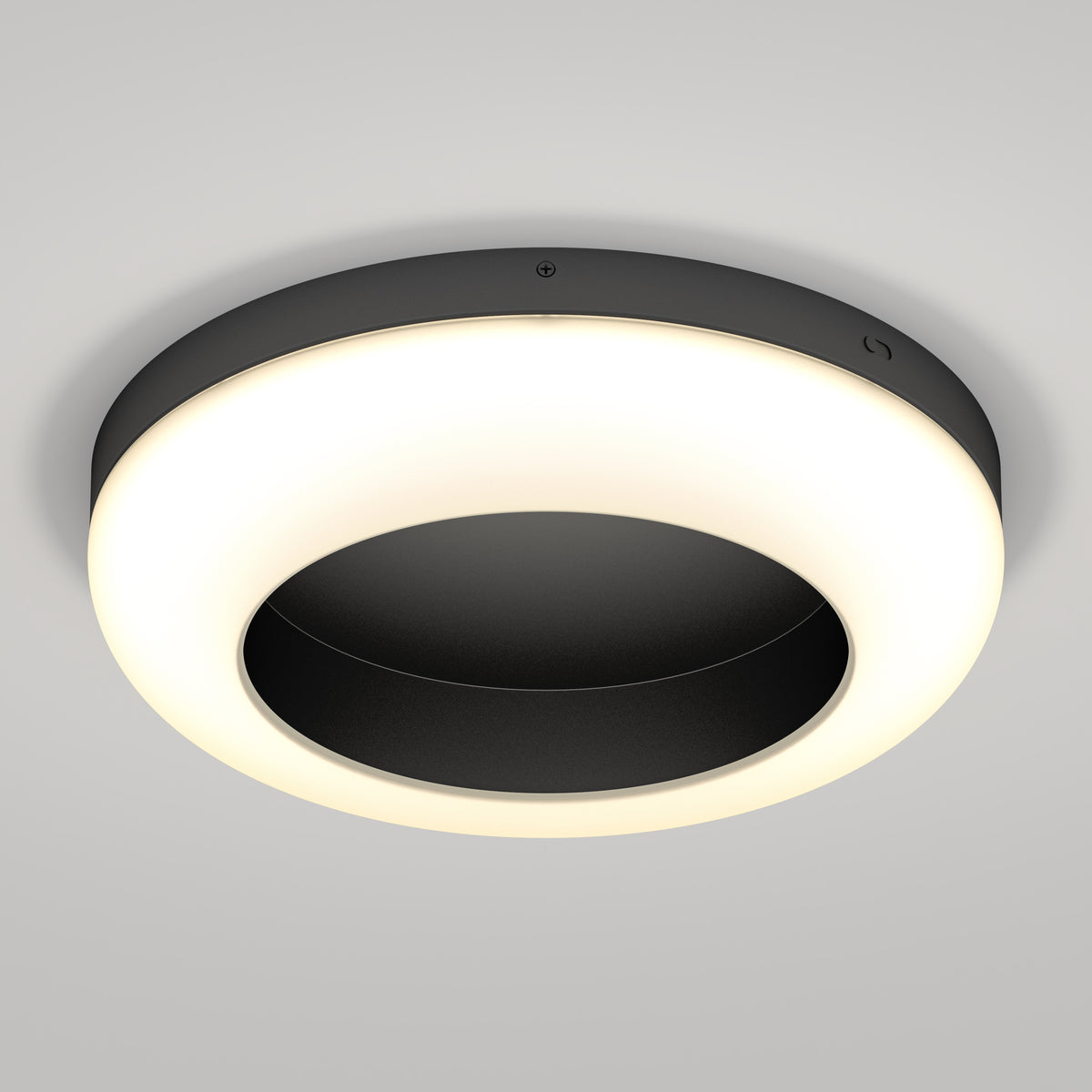 A modern, circular ceiling light fixture with a black center and a glowing white ring, mounted on a smooth, light gray ceiling.