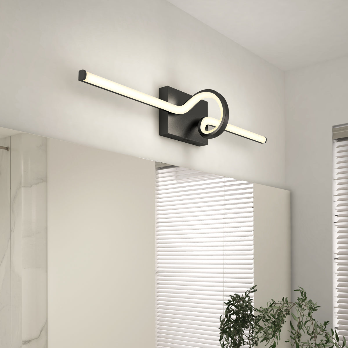 A modern wall-mounted LED light with a rectangular black base and a glowing tube that loops in a knot-like shape, installed above a bathroom mirror near a window with white blinds and a green plant.