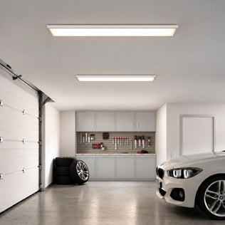 Two Artika Skyshade 48 in. x 12 in. (121 x 30 cm) Modern Ceiling Light RGB panels mounted in a garage with cabinets, tools, tires, and a white car.