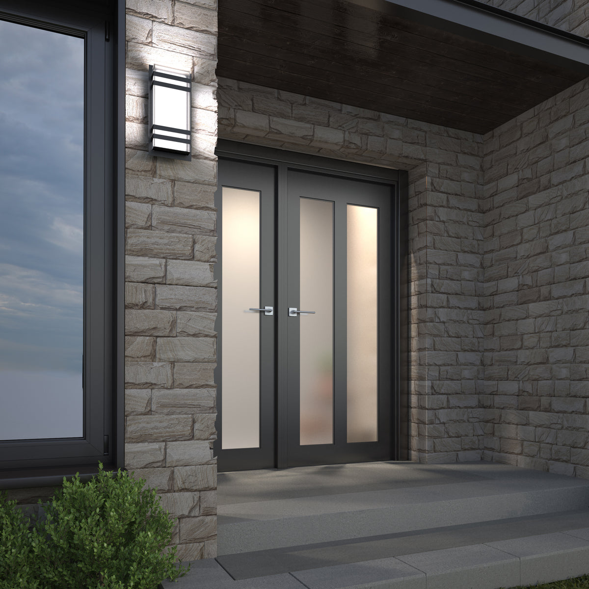 Modern double front doors with frosted glass panels set in a stone exterior wall, illuminated by a rectangular wall light, with steps and greenery in the foreground.