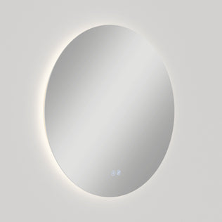 The Artika Raya 24 in. LED mirror features a round, wall-mounted design with a soft backlight and integrated defogger. Two small touch buttons appear at the bottom center of the mirrors surface against a plain white background.