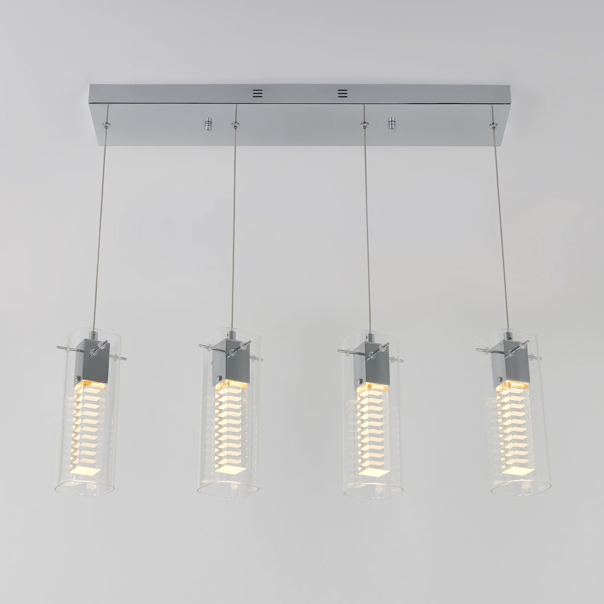 The Artika Hologram 4-light LED pendant features four cylindrical glass-shaded pendants with vertical LED bulbs, all suspended from a sleek rectangular chrome base.