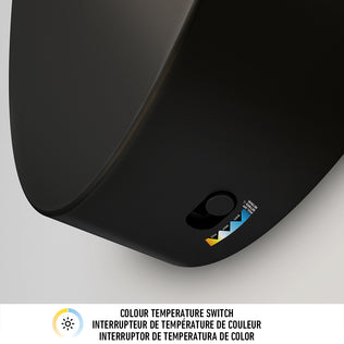 Close-up of the Artika DNA modern LED wall sconce 3 CCT in black, featuring a small switch with colored triangles for color temperature options. Text below reads "Colour Temperature Switch" in English, French, and Spanish.