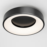 A modern, round ceiling light fixture with a black outer ring and a glowing circular white center, mounted on a white ceiling.