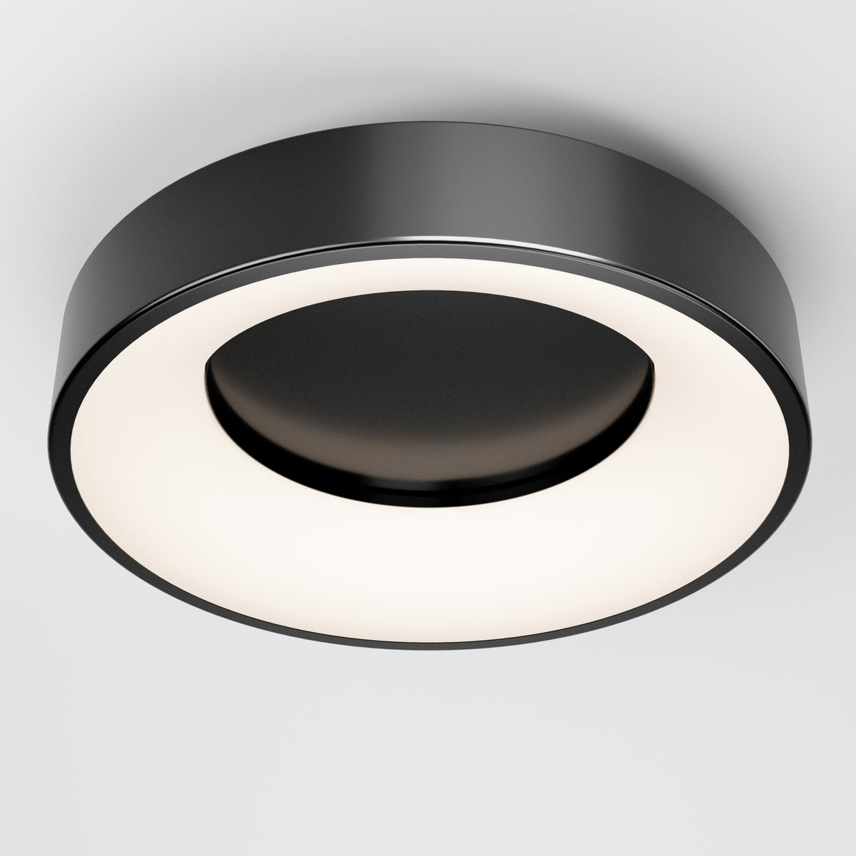 The Artika Aiden LED flush mount features a modern circular design with a matte black outer ring and glowing white inner ring, seamlessly mounted on a white ceiling.