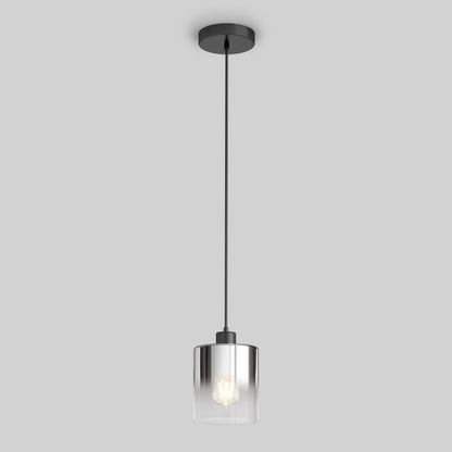 The Artika Haze pendant light glass features a clear cylindrical shade, black ceiling mount, and black cord. The illuminated bulb hangs against a plain gray background, offering modern style.