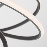 Close-up of modern, curved LED light fixtures with sleek black and white elements, forming abstract, overlapping loops against a plain, light background.