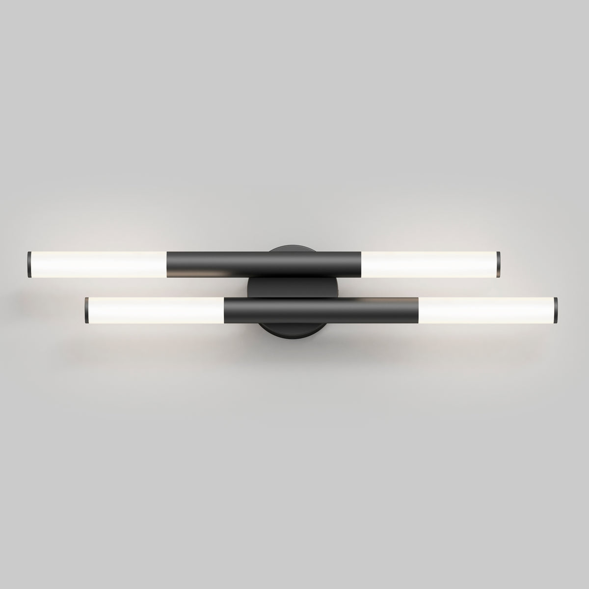 Modern wall-mounted light fixture with two horizontal, cylindrical LED bars intersecting at a central round black base, set against a plain gray background. The bars are black and white, emitting a soft light.
