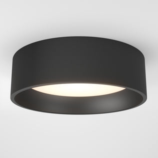The Artika Alton LED flush mount is a modern circular black ceiling light installed on a white ceiling, emitting a soft white glow from its center.