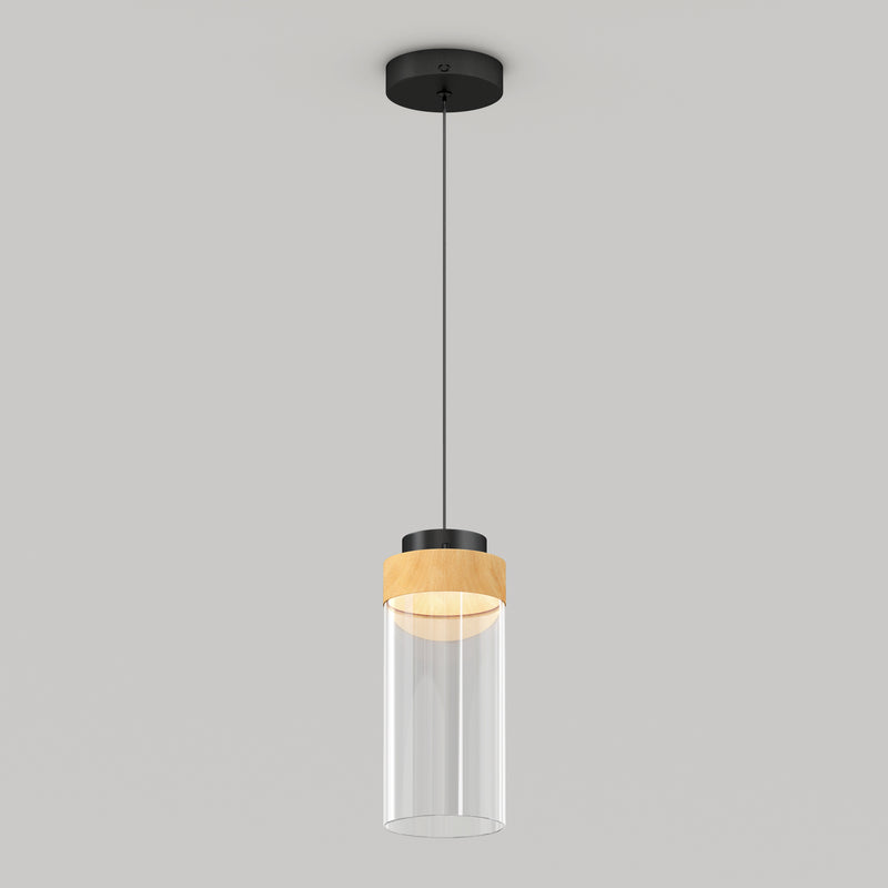 The Artika Hanson 1-light LED pendant 5 CCT features a black ceiling mount, black cord, wooden accent, and clear cylindrical glass shade, shown against a plain light gray background.