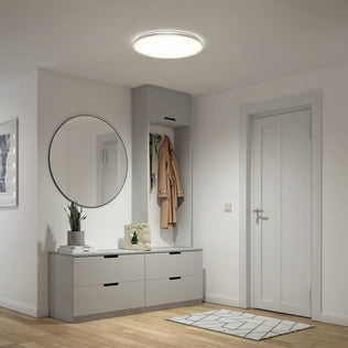 Modern entryway with round mirror, gray cabinets, coat rack, plant, and Artika Jupiter 23" LED flush mount light with remote above.