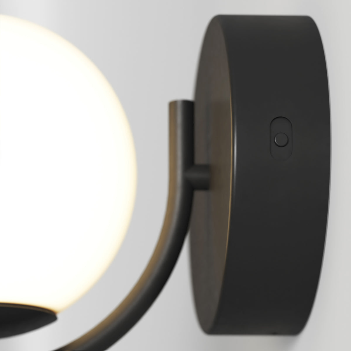 Close-up of the Artika Bloom LED Sconce 3 CCT, a modern wall-mounted fixture with a round white shade and black base featuring a small circular switch.