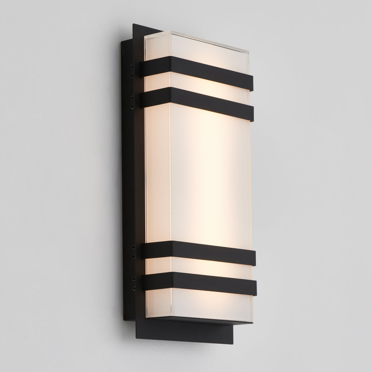 The Artika Glowbox 3 indoor-outdoor LED wall light features a modern rectangular design with a frosted glass shade framed by three horizontal black metal bands, mounted on a black backplate against a light gray wall.