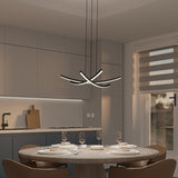 Modern kitchen with gray cabinets and a round dining table set for five. Contemporary black and white chandelier hangs above. Window with striped blinds lets in natural light. Warm, minimalist decor.