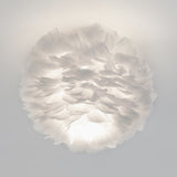 A round, white ceiling light fixture made of layered, soft feathers, creating a fluffy, cloud-like appearance with gentle, diffused illumination.
