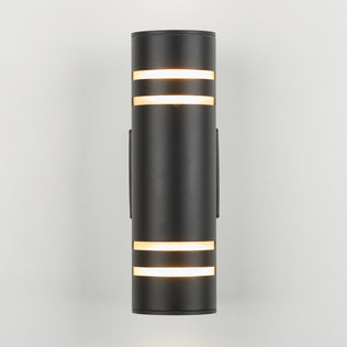 The Artika V3 indoor-outdoor wall light is a modern black cylindrical sconce with horizontal slits near the top and bottom, casting warm light against a plain white background.