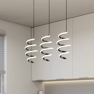 Three Artika Chorus 3-light LED pendant lights hang above white cabinets in a minimalist kitchen, casting a soft white glow that enhances the space’s clean, contemporary look.