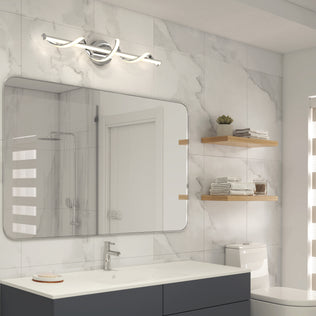 Modern bathroom with large mirror, marble tile walls, white sink, chrome faucet, Artika Coda modern LED bathroom vanity light 5 CCT, floating wooden shelves holding towels and decor, and a toilet beneath the shelves.
