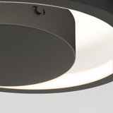Close-up of a modern, circular ceiling light fixture with a matte black finish and a glowing white ring emitting soft light. The image highlights the fixture’s sleek, minimalist design.