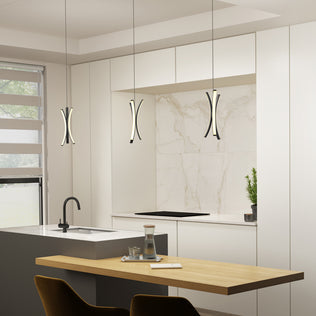 A modern kitchen featuring white cabinets, marble backsplash, a small potted plant, an island with a black faucet, a wooden dining table set with glassware, and Artika's Corben Pendant LED light 5CCT Black.