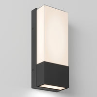 The Artika Dixon indoor-outdoor LED wall light features a modern rectangular design with a black base and frosted white glass shade, mounted on a light gray wall and emitting soft, even illumination.