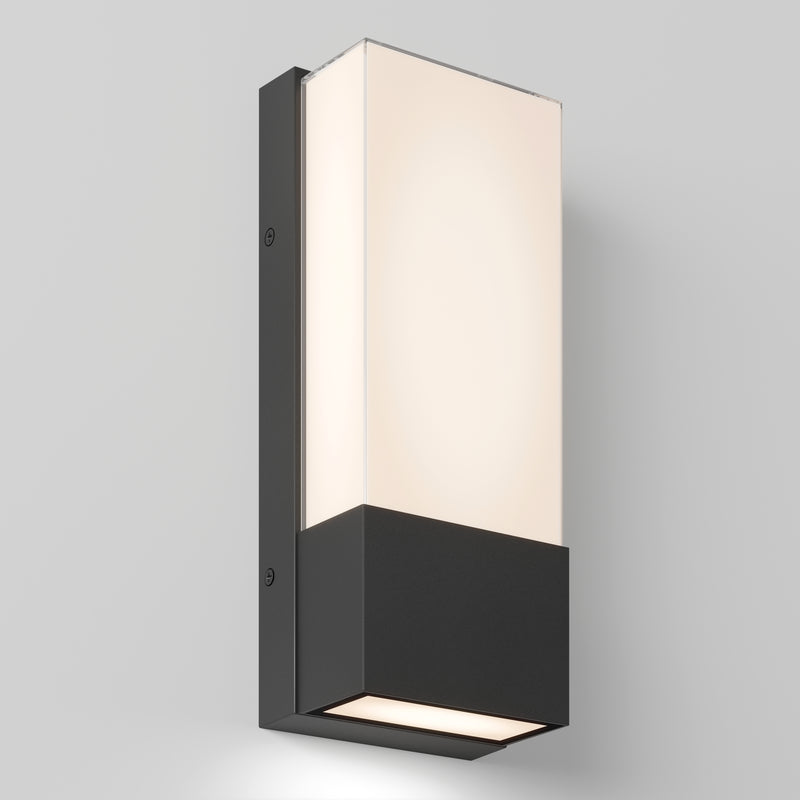 The Artika Dixon indoor-outdoor LED wall light features a modern rectangular design with a black base and frosted white glass shade, mounted on a light gray wall and emitting soft, even illumination.