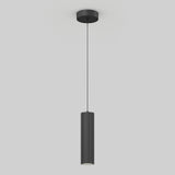 A modern black pendant light with a cylindrical, vertically grooved shade hanging from a thin cord attached to a round ceiling mount, set against a plain light gray background.