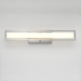 A modern rectangular wall-mounted light fixture with a sleek metal frame and a long, horizontal frosted glass shade, emitting a soft white glow against a plain light-colored wall.