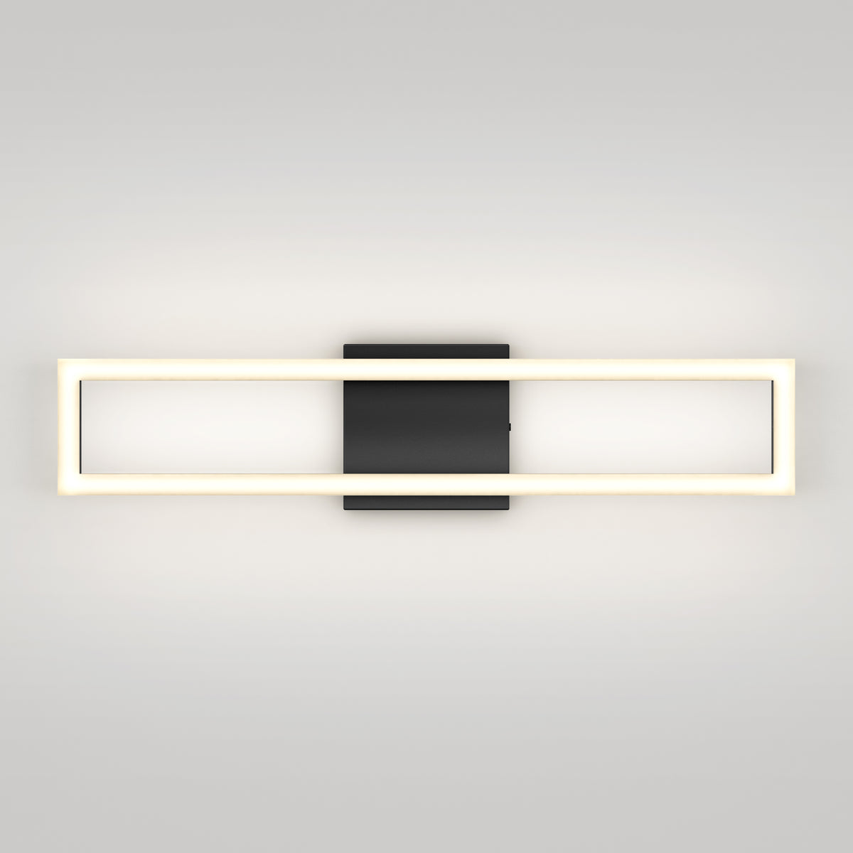 A modern wall sconce with a rectangular, illuminated frame and a central black square mounting plate, set against a plain light-colored wall.