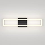 A modern wall sconce with a rectangular, illuminated frame and a central black square mounting plate, set against a plain light-colored wall.
