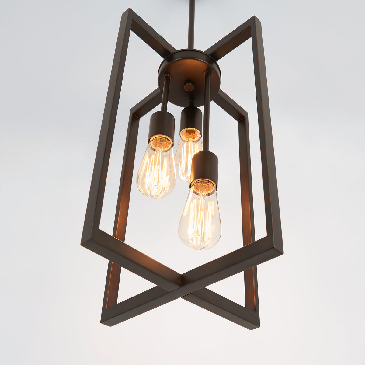 A geometric pendant light fixture with three exposed Edison bulbs, featuring a dark metal frame in an angular, open design, hanging from the ceiling against a plain white background.
