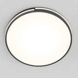 A round, modern ceiling light fixture with a black rim emits a bright white glow against a plain gray ceiling.