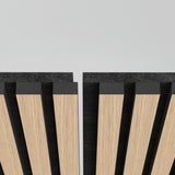 A close-up of modern wall or ceiling panels made of light wood slats with dark gaps between them, arranged vertically with a gap in the center and a clean, light gray background.