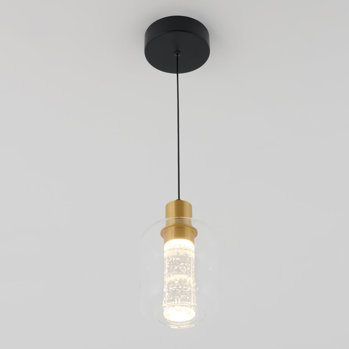 The Champagne Globe modern LED pendant light by Artika features a black circular mount, slim black cord, and a glass shade with gold accents and a glowing textured bulb, shown suspended against a plain white background.