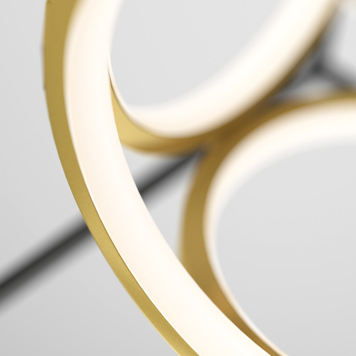 Close-up of two overlapping circular light fixtures with a gold finish and soft white glow, set against a neutral blurred background.