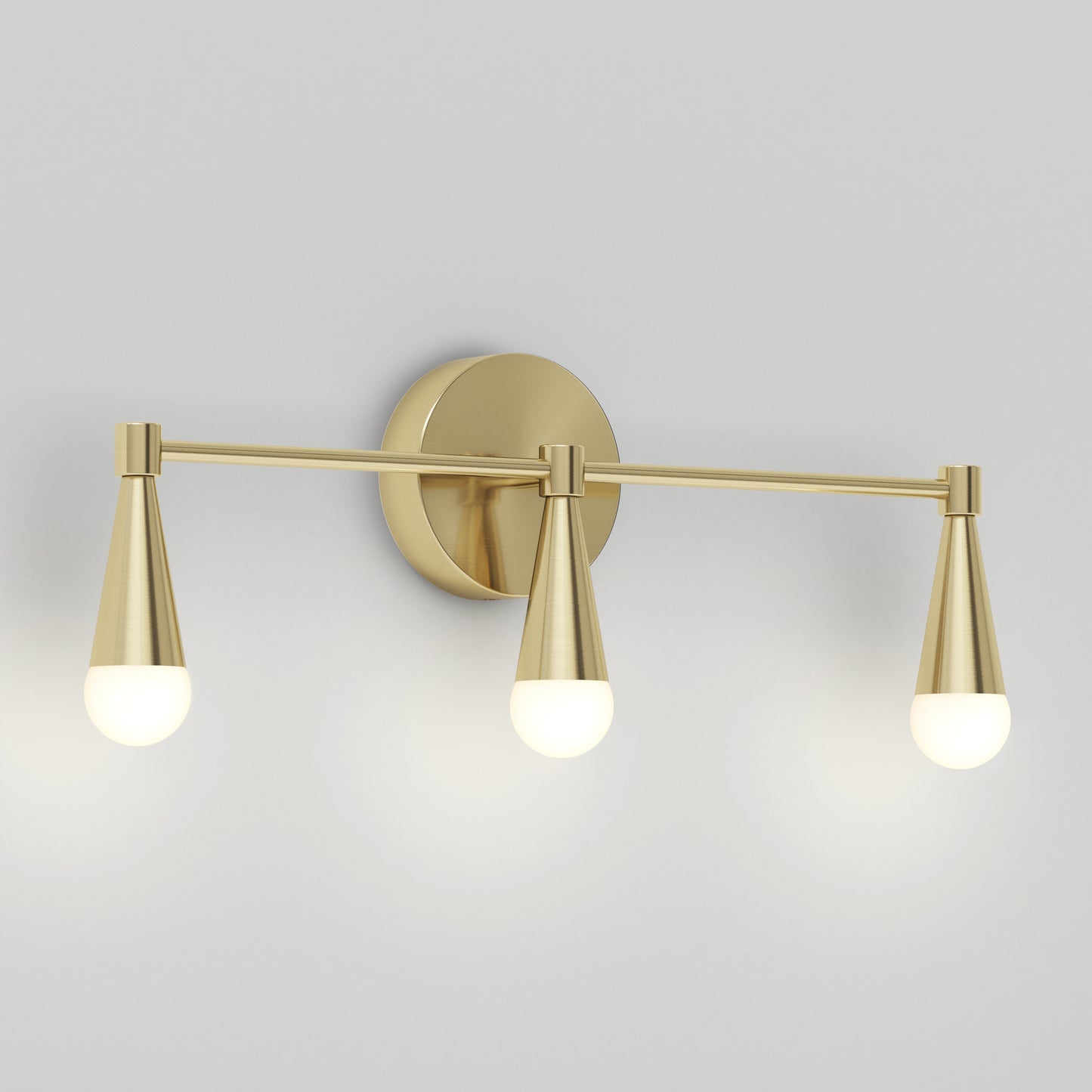 The Artika Wayden LED mid-century bathroom vanity light 3 CCT features a brushed gold finish, three downward cone arms with round frosted bulbs, and a circular backplate mounted on a light gray wall.