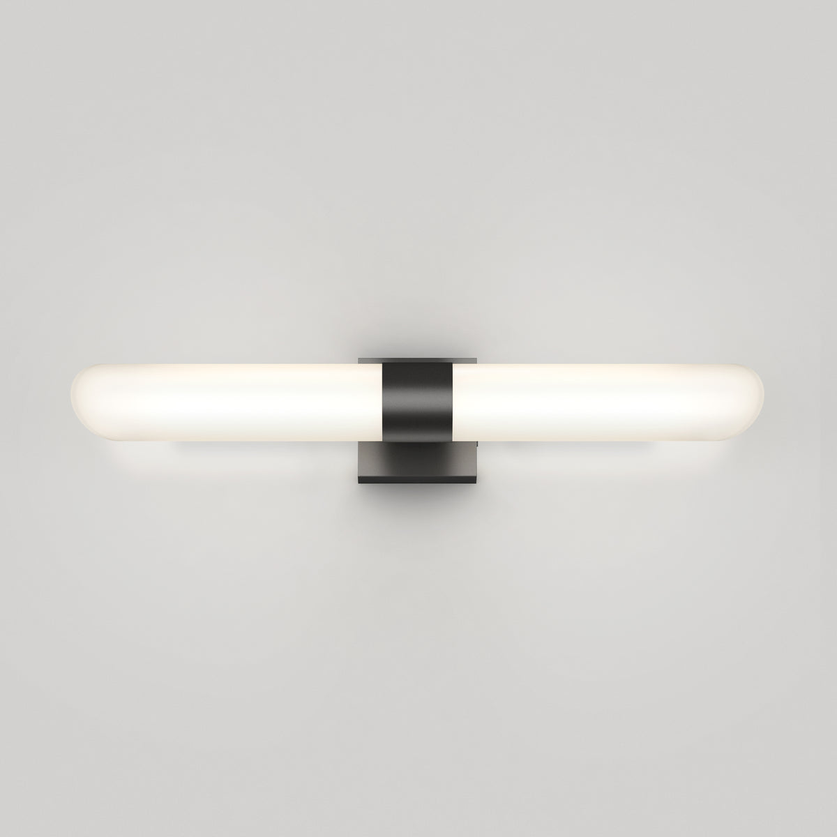Minimalist wall-mounted light fixture with a horizontal frosted glass tube and a central black rectangular base, glowing softly against a plain light gray background.