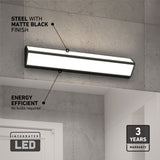 Rectangular LED wall light with matte black finish mounted on a gray tiled wall, labeled as energy efficient with no bulbs required; features a 3-year warranty badge in the bottom right corner.