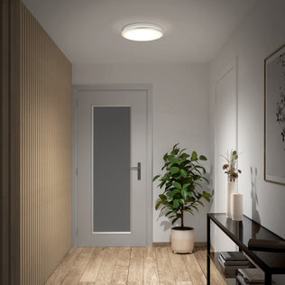 Modern hallway with wooden floor, potted plant, decor, and artwork lit by the Artika Vera 13 in. LED Flush Mount Ceiling Light.