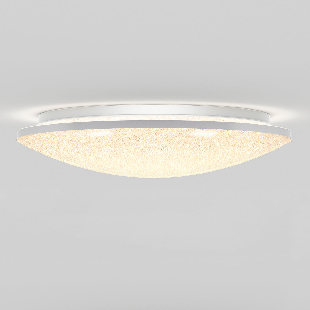 A modern, dome-shaped ceiling light fixture with a frosted, textured cover emits a soft, warm glow against a plain white ceiling.
