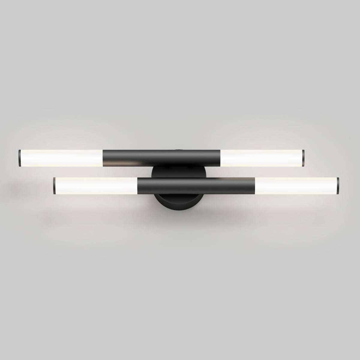 A modern wall light fixture with two parallel, cylindrical LED tubes in black and white, mounted on a round black base against a plain grey background.