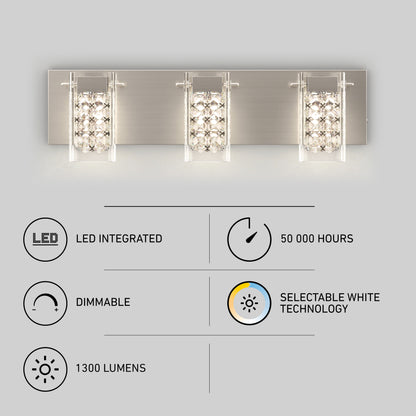 A modern three-light wall fixture with crystal and glass shades, mounted on a brushed metal plate. Below are icons and text indicating LED integrated, 50,000 hours, dimmable, selectable white technology, and 1300 lumens.