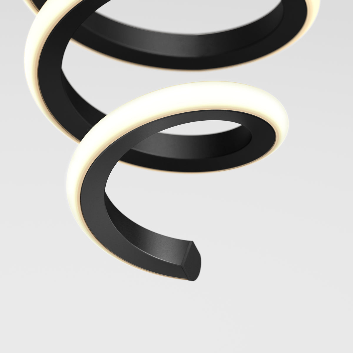 A close-up of a modern, black spiral-shaped light fixture with a glowing white edge, set against a plain light gray background.