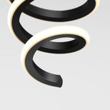 A close-up of a modern, black spiral-shaped light fixture with a glowing white edge, set against a plain light gray background.